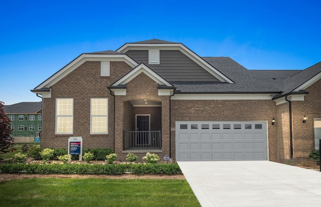 view of front of home with brick siding, a front yard, roof with shingles, a garage, and driveway