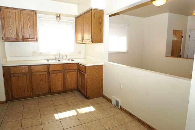 kitchen with a sink, visible vents, brown cabinets, and light tile patterned floors