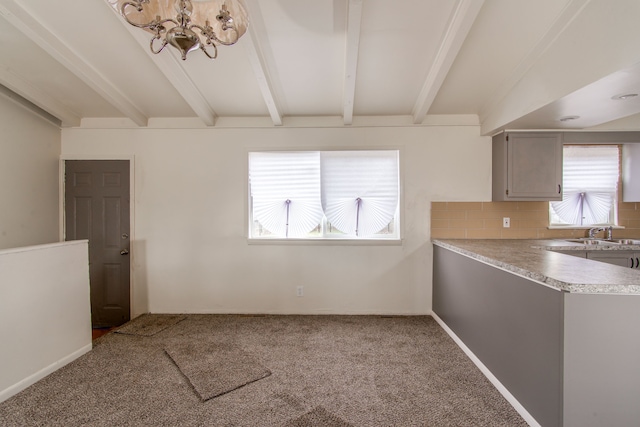 unfurnished dining area with beam ceiling, carpet flooring, and a sink