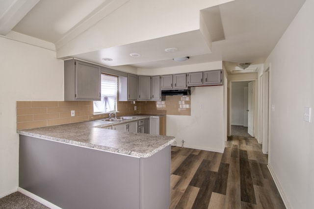 kitchen with backsplash, under cabinet range hood, vaulted ceiling, gray cabinets, and a peninsula