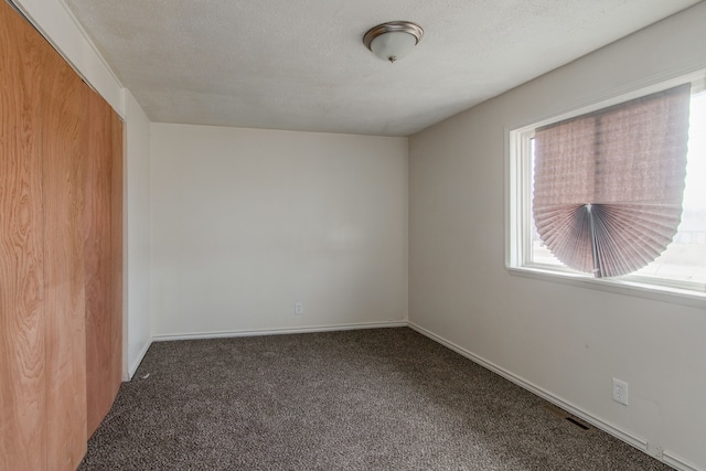 carpeted empty room with baseboards and a textured ceiling