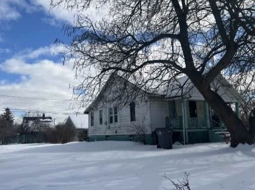 view of snowy exterior featuring covered porch