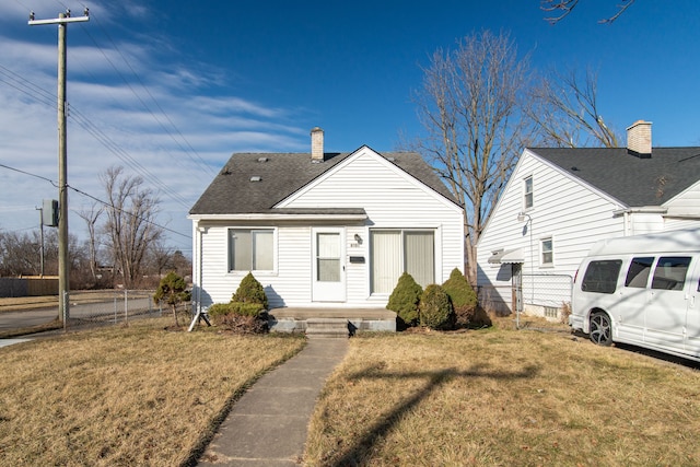 view of front of home with fence, a front yard, roof with shingles, and a chimney