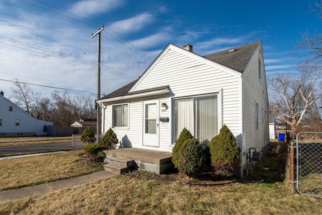 bungalow-style house featuring a shingled roof, a front lawn, fence, and a gate