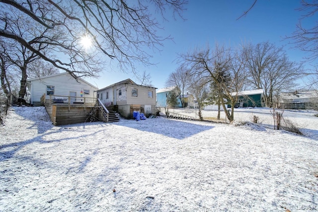 snow covered back of property with stairway, fence, and a wooden deck