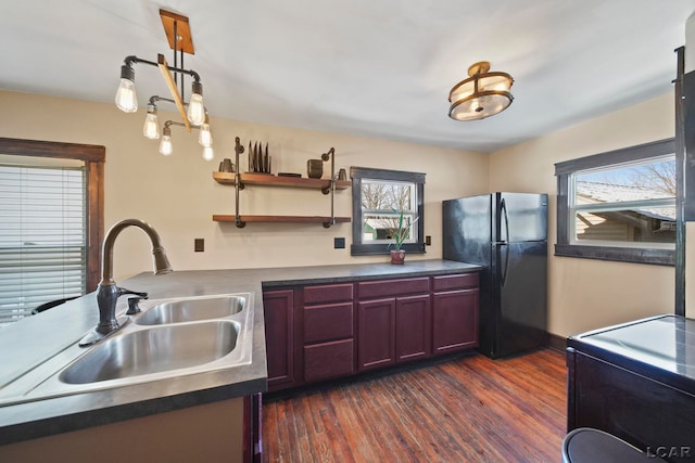 kitchen with dark wood-type flooring, a sink, dark countertops, freestanding refrigerator, and dark brown cabinets