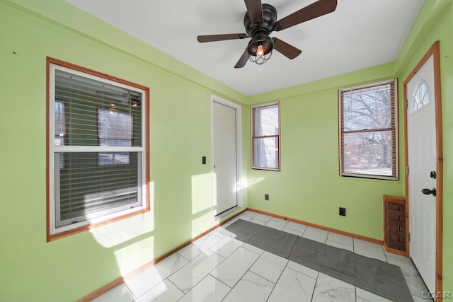 unfurnished room with ceiling fan and baseboards