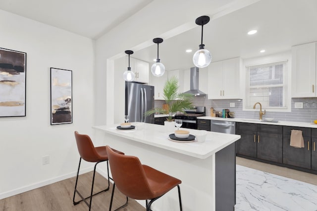 kitchen with a sink, stainless steel appliances, white cabinetry, wall chimney exhaust hood, and tasteful backsplash