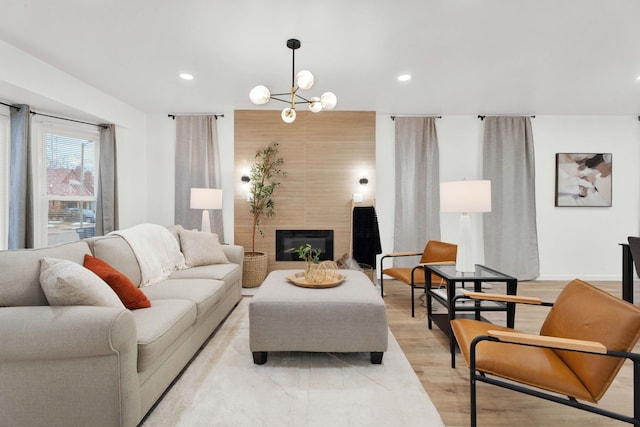 living room featuring a large fireplace, baseboards, recessed lighting, light wood-style floors, and a notable chandelier