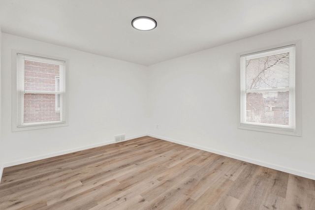 spare room featuring baseboards, plenty of natural light, and wood finished floors