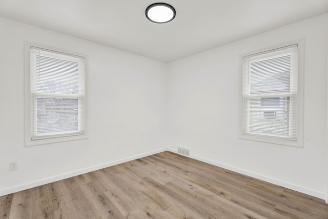 unfurnished room with wood finished floors, baseboards, and visible vents