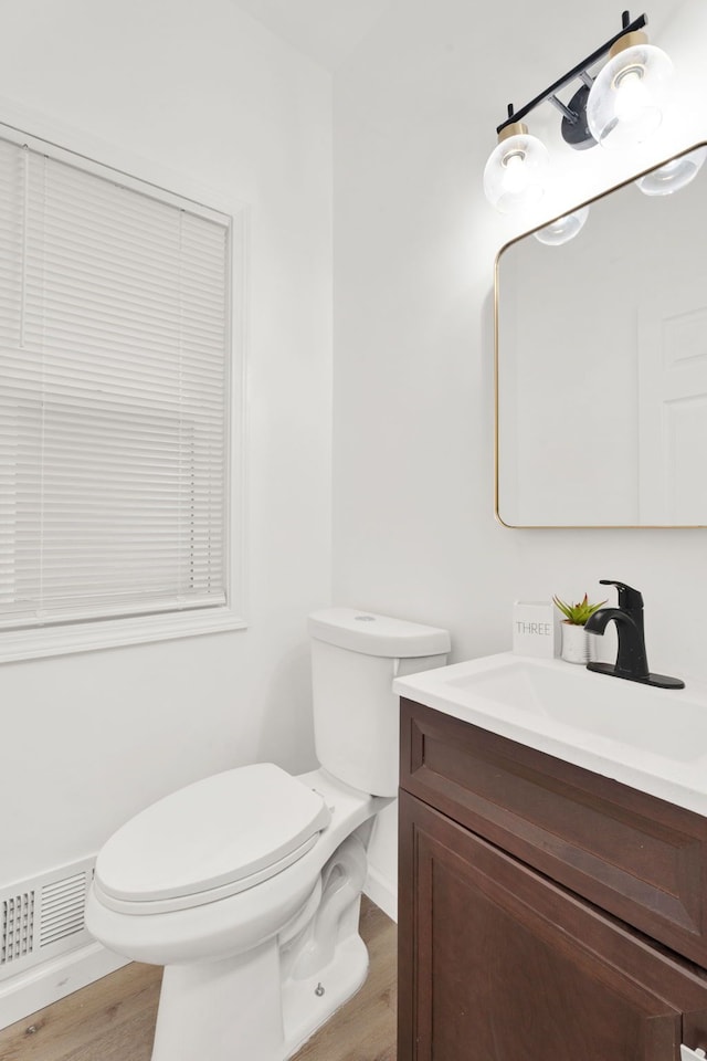 bathroom with vanity, wood finished floors, visible vents, baseboards, and toilet