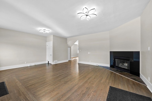 unfurnished living room featuring visible vents, wood finished floors, a multi sided fireplace, and baseboards