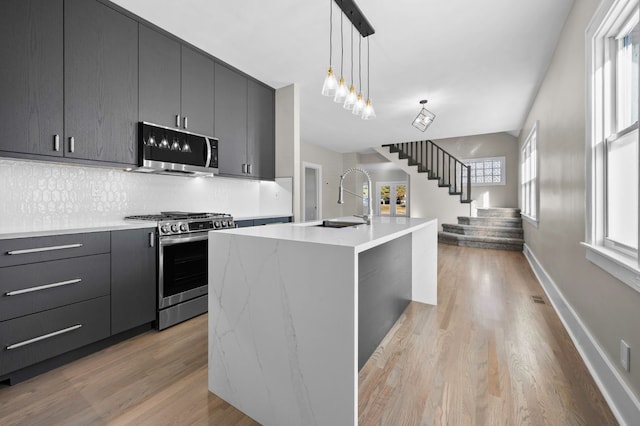 kitchen with decorative light fixtures, appliances with stainless steel finishes, modern cabinets, and light wood-style floors