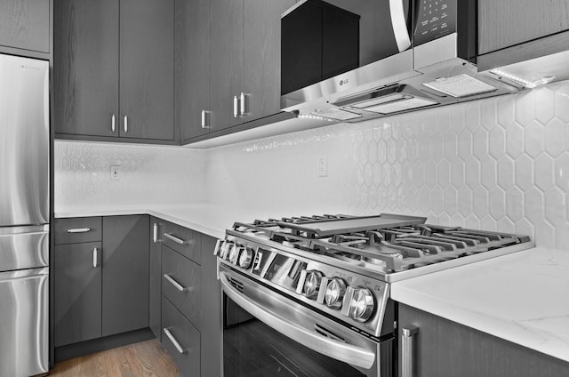 kitchen with decorative backsplash, light wood-style floors, appliances with stainless steel finishes, and gray cabinetry