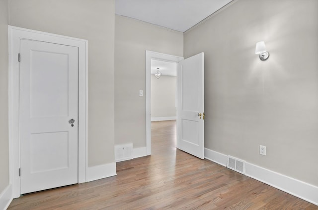 unfurnished room featuring wood finished floors, visible vents, and baseboards