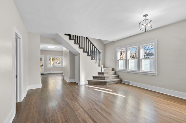 entryway featuring visible vents, dark wood finished floors, baseboards, a chandelier, and stairs