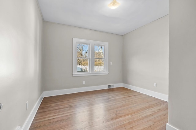 empty room featuring visible vents, baseboards, and wood finished floors