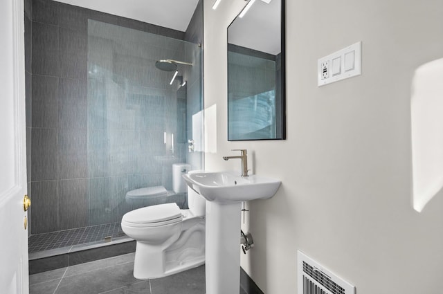 full bathroom featuring visible vents, tiled shower, toilet, and tile patterned flooring