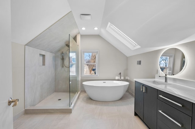 bathroom with vanity, tiled shower, a freestanding tub, recessed lighting, and lofted ceiling with skylight