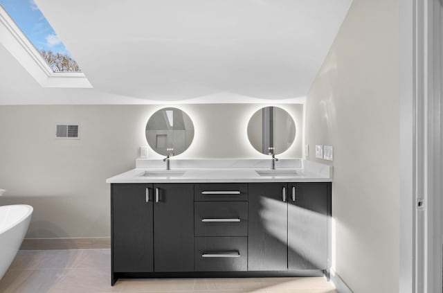 full bath featuring double vanity, a sink, a freestanding tub, and a skylight