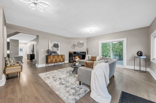 living room featuring a glass covered fireplace, baseboards, and wood finished floors