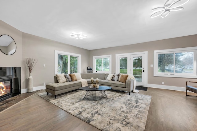 living area featuring a glass covered fireplace, baseboards, and wood finished floors