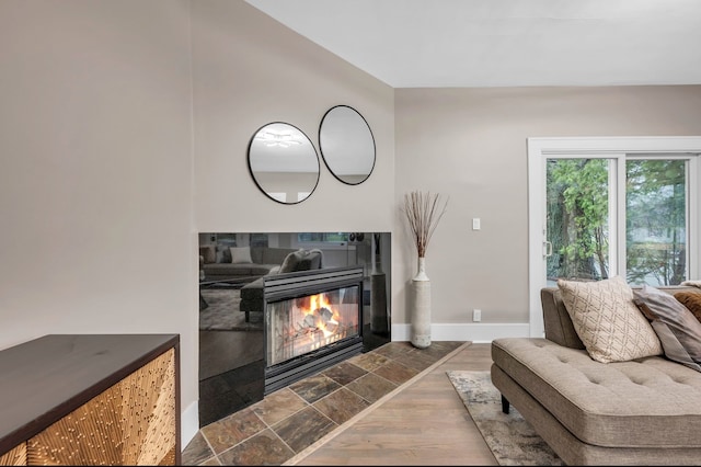 living room with baseboards, a tiled fireplace, and dark wood-style flooring