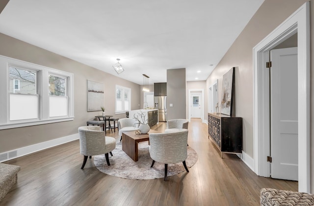 living room featuring baseboards, visible vents, and wood finished floors