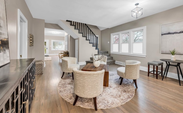living area with a wealth of natural light, baseboards, stairway, and wood finished floors