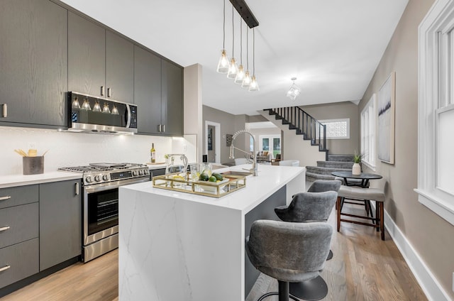 kitchen with gray cabinetry, open floor plan, light countertops, and appliances with stainless steel finishes