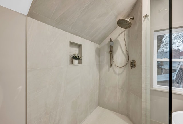 full bathroom featuring a tile shower and vaulted ceiling