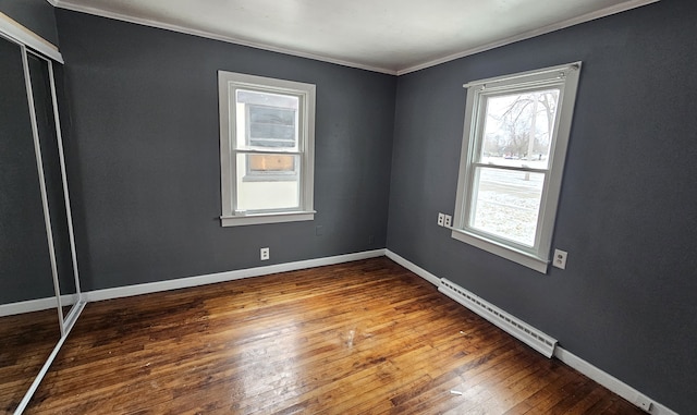 spare room with baseboards, baseboard heating, crown molding, and hardwood / wood-style flooring