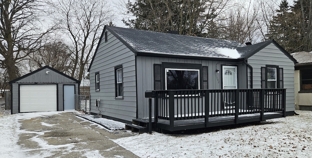 view of front of home featuring an outbuilding, driveway, a detached garage, and roof with shingles