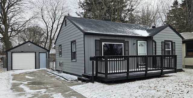 view of front of home featuring an outbuilding, driveway, a detached garage, and roof with shingles