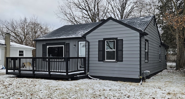 snow covered property featuring a shingled roof and a deck