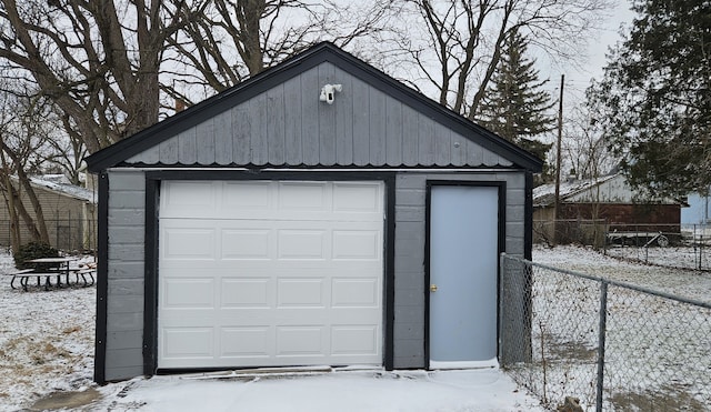 snow covered garage featuring fence