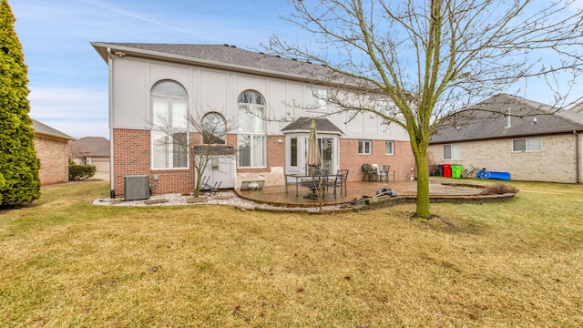 back of property with a patio, central AC unit, a shingled roof, a lawn, and brick siding