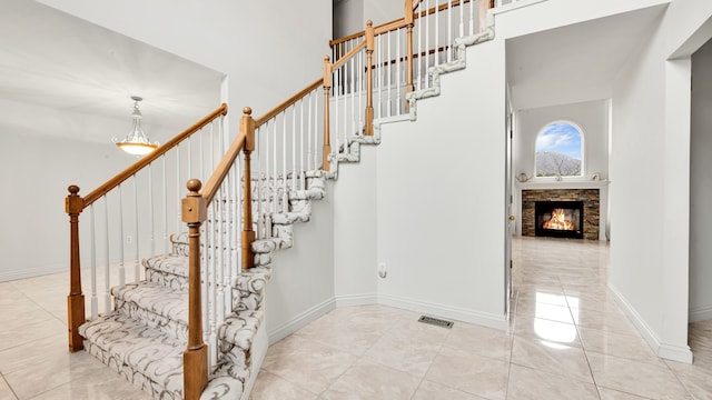 stairs featuring tile patterned floors, visible vents, a fireplace, and baseboards