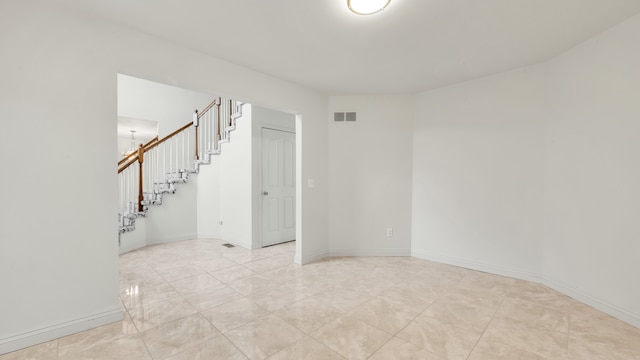 empty room featuring visible vents, baseboards, and stairs