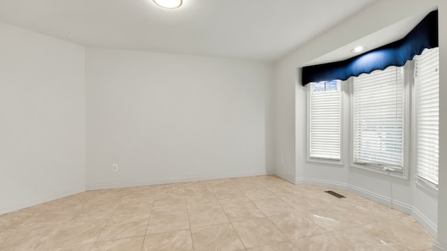 empty room featuring light tile patterned floors, visible vents, and baseboards