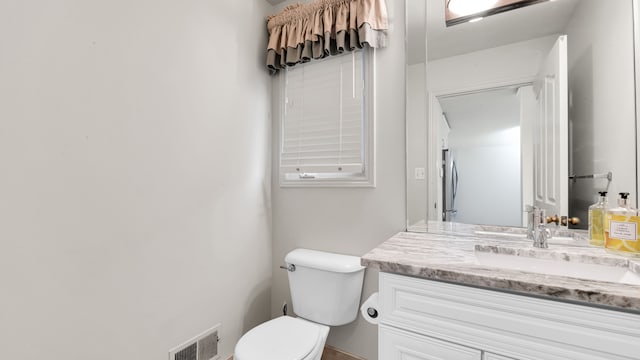 half bathroom featuring vanity, toilet, and visible vents