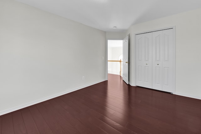 unfurnished bedroom featuring dark wood finished floors, baseboards, and a closet