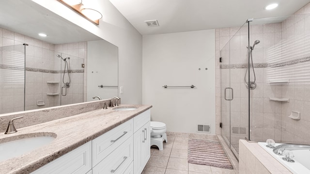 bathroom featuring tile patterned flooring, double vanity, a stall shower, and a sink