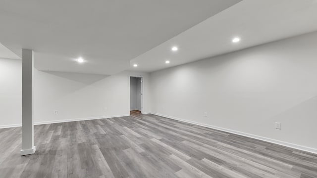 finished below grade area featuring recessed lighting, baseboards, and wood finished floors