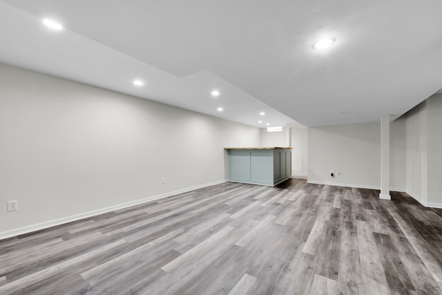 finished basement with recessed lighting, baseboards, wood finished floors, and a dry bar