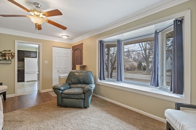 sitting room featuring a ceiling fan, crown molding, baseboards, and wood finished floors