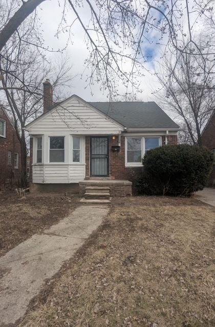 bungalow-style house with brick siding and a chimney