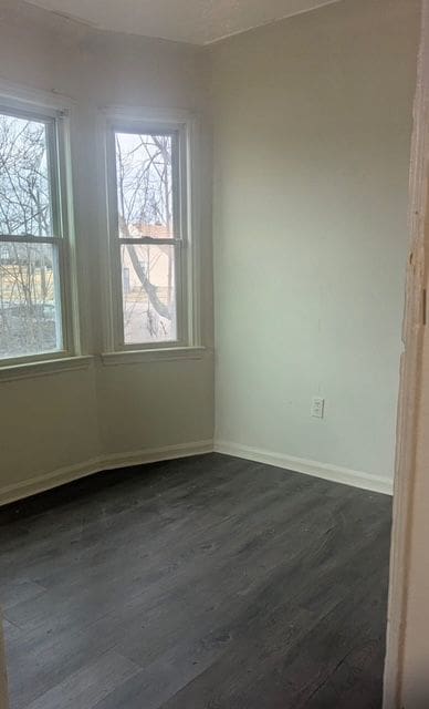 unfurnished room featuring dark wood-type flooring and baseboards