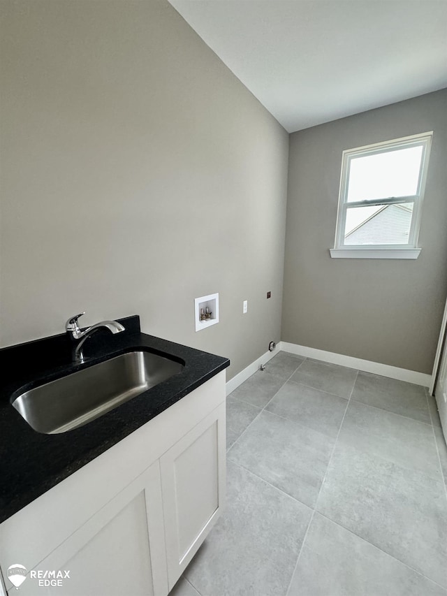 laundry room featuring hookup for a washing machine, light tile patterned floors, baseboards, cabinet space, and a sink